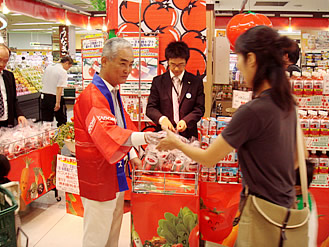 喜岡会長（当時社長）による生トマト配布（2007年8月　スーパー店頭で）